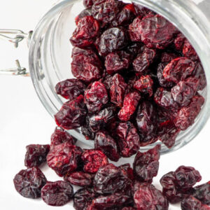 Close up selective focus dried cranberries in a glass jar on a white background